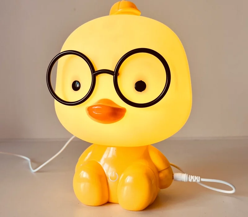 Kurczątko z okularami lampka nocna dziecięca LED, lampka nocna Kurczątko dziecięca, dla dzieci. Ładowanie przez USB sprawia, że jest praktyczna i wygodna. Bezpieczna dla dzieci, dostępna w kolorze żółtym.
